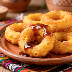 Traditional Peruvian Picarones with Chancaca Syrup on Rustic Plate
