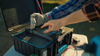 Technician working on electronic equipment outdoors with tools and safe practices in the afternoon...