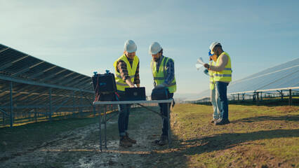 Team inspecting solar panels at a renewable energy site during a sunny afternoon