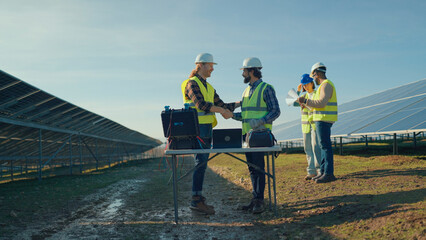 Workers discuss solar energy project progress at a renewable energy site in bright daylight
