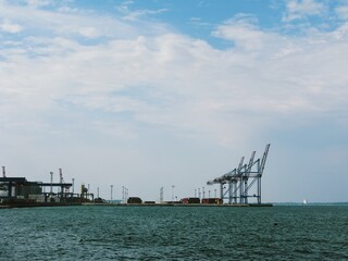 Fototapeta premium Cargo cranes of modern sea terminal under wide cloudy sky 