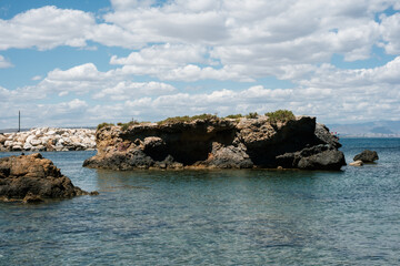 Fototapeta premium Coastal rock formations with clear blue water under a cloudy sky