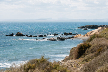 Scenic coastal landscape with rocky shoreline and distant horizon under cloudy sky