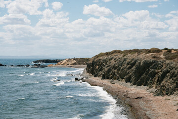 Scenic coastal landscape with rocky shoreline and blue ocean under cloudy sky