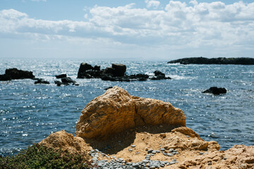 Scenic coastal rock formation against sparkling ocean waves under cloudy sky