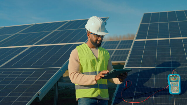 Technician checks solar panel system performance during daylight hours at a renewable energy site