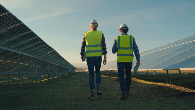 Two workers review solar panels at a renewable energy installation in the late afternoon sun