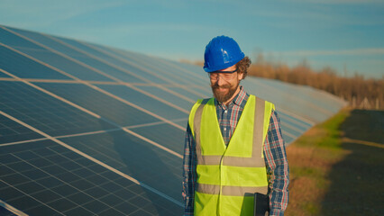 Engineer inspecting solar panels in green energy project at sunset in rural area