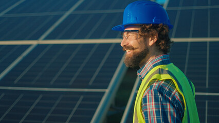Smiling worker inspects solar panels at a renewable energy site during the afternoon