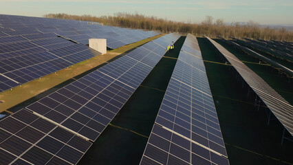 Large solar farm showcasing solar panels with workers inspecting system in the afternoon sunlight © Videophilia
