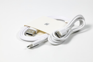 New white USB type charger cable in paper pack, compatible for many devices, wrapped in a spiral...