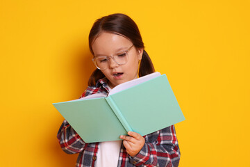 Fototapeta premium Cute little girl reading book on orange background