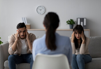 Psychologist sits facing young arab couple who are struggling with relationship problems. The...