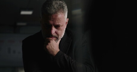 Obraz premium Business executive lost in thought with hand on chin during difficult company meeting in corporate boardroom with performance charts in background
