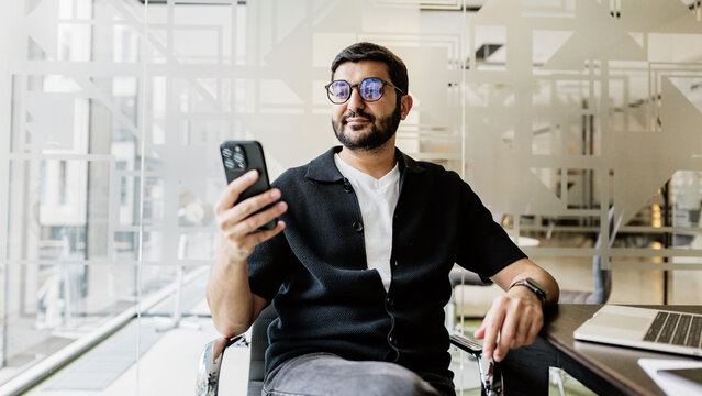 Man using smartphone at modern office workspace - Powered by Adobe