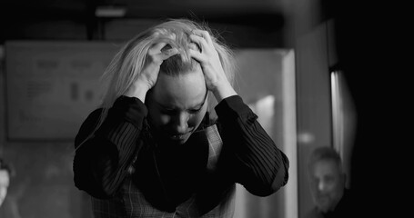 Businesswoman in black and white photo holding head in hands, overwhelmed by stress during intense...