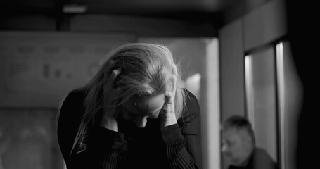 Businesswoman in black and white photo holding head in hands, overwhelmed by stress during intense...