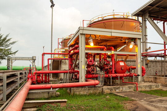 Industrial facility with large storage tanks and red pipes, representing manufacturing and energy production