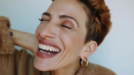 Smiling woman enjoys a playful moment while posing for the camera in a cozy sweater during daylight