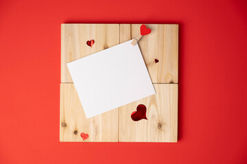 Blank white card template on square wood blocks with hearts, red background. Vertical