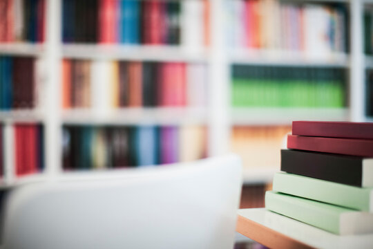 Stack of books in office with book shelf in background
