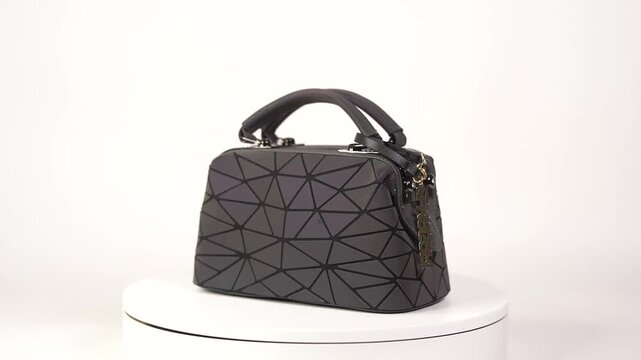 Valmiera, Latvia - November 12, 2020: Stylish black geometric handbag showcased on a pedestal, camera pans to reveal intricate design details