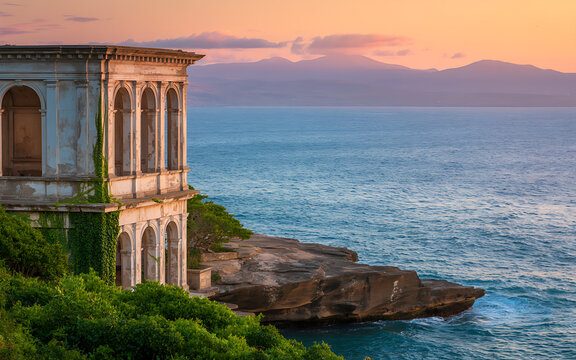 Elegant historic building perched on a cliff overlooking the ocean at sunset