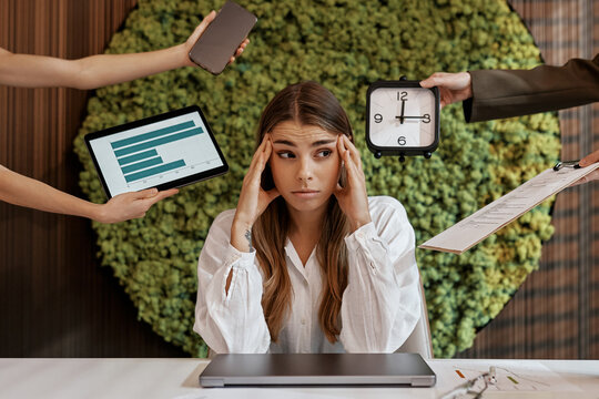Stressed businesswoman overwhelmed with tasks in modern office
