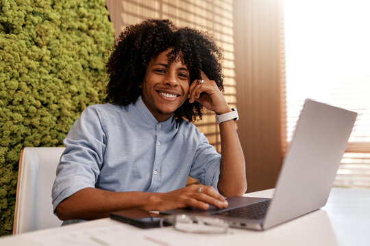 Focused young afro man working on laptop in eco-friendly office interior