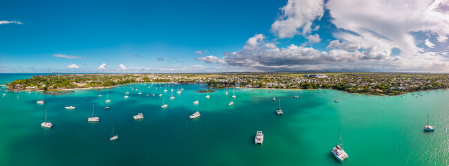 Grand Baie, Mauritius panoramic bay with catamarans sailboats and motorboats over emerald sea under wide summer sky