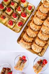 Overhead view of assorted canapes and dumplings on gold trays at luxury catering event