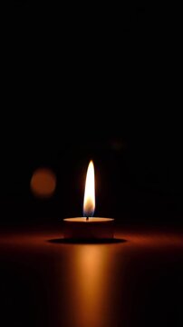 An award-winning, ultra-cinematic indoor scene focused on a single candle burning in a quiet, dim room. The candle sits on a simple wooden table. The flame flickers very softly &mdash; gentle, controlled,
