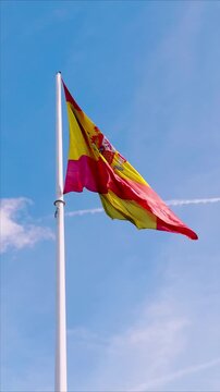 A Spanish flag waving in the wind, displaying its vibrant red and yellow colours against the natural outdoor light.
