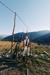 Fototapeta premium Violin man mountains meadow fence musician outdoors landscape standing with instrument in rural valley, portrait in natural sunlight, scenic travel and creative music lifestyle image