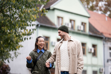 Happy diverse couple walking holding hands outdoors