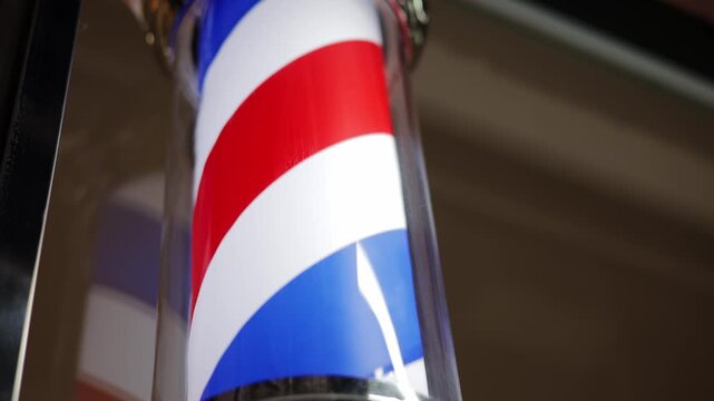 Barbershop pole sign board cylindrical sign in vintage hairdresser spinning on dark background.