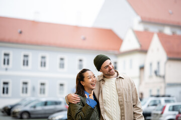 Happy young diverse couple laughing on city street