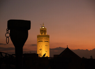 Night view of the illuminated Koutoubia Mosque tower in Marrakech, highlighting its warm lights and iconic Moroccan architecture.