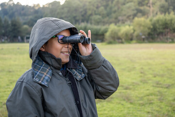 Young mexican boy exploring nature with binoculars, enjoying outdoor birdwatching