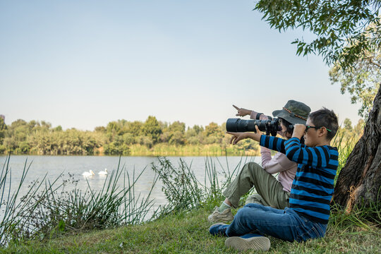 Mother and son birdwatching by the lake, enjoying nature and a family outdoor activity