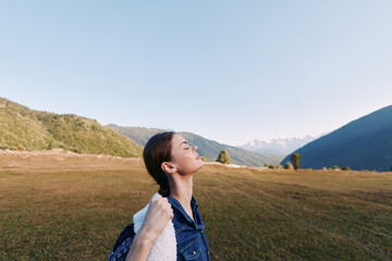 Fototapeta premium Woman with backpack in mountain meadow enjoying fresh air and nature, hiking and travel portrait with closed eyes, peaceful scenic landscape and relaxed outdoor adventure.