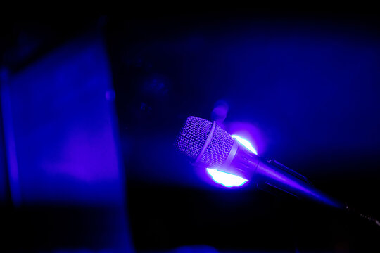Close-up of microphone on stage in blue lighting at live music event