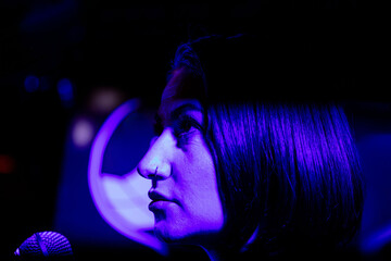 Female singer in purple spotlight with microphone