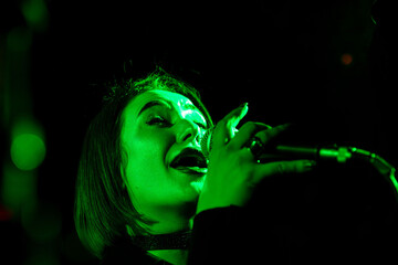 Female singer performing under green light at live concert