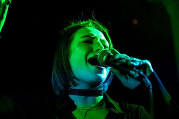 Female singer performing at concert under green lights