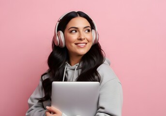Young Woman Smiling with Headphones and Laptop, Listening to Music or Working, Pink Background.