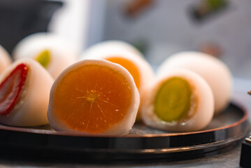 Close up shows strawberry, grape, and halved mandarin daifuku on a lacquered tray in Kyoto, Japan. Warm light and shallow depth reveal glossy fruit and soft mochi.