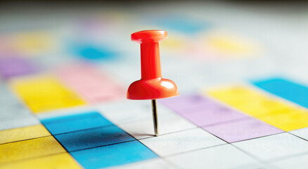 red drawing pin, push pin on a blank calendar piece of paper
