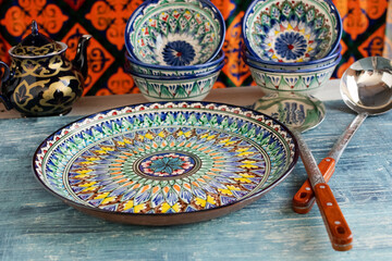 Traditional Uzbek ceramic dishes and teapot with vibrant oriental patterns. Kitchen utensils and...