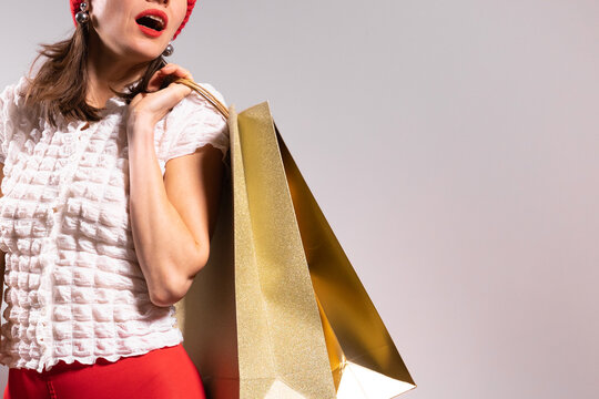 Winter Christmas shopping woman with shopping bags wearing red hat over light background - Powered by Adobe